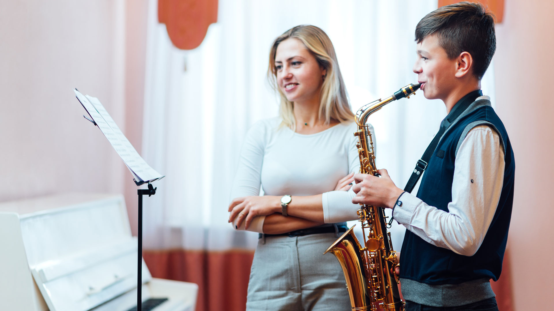 female music teacher teaching boy the saxophone