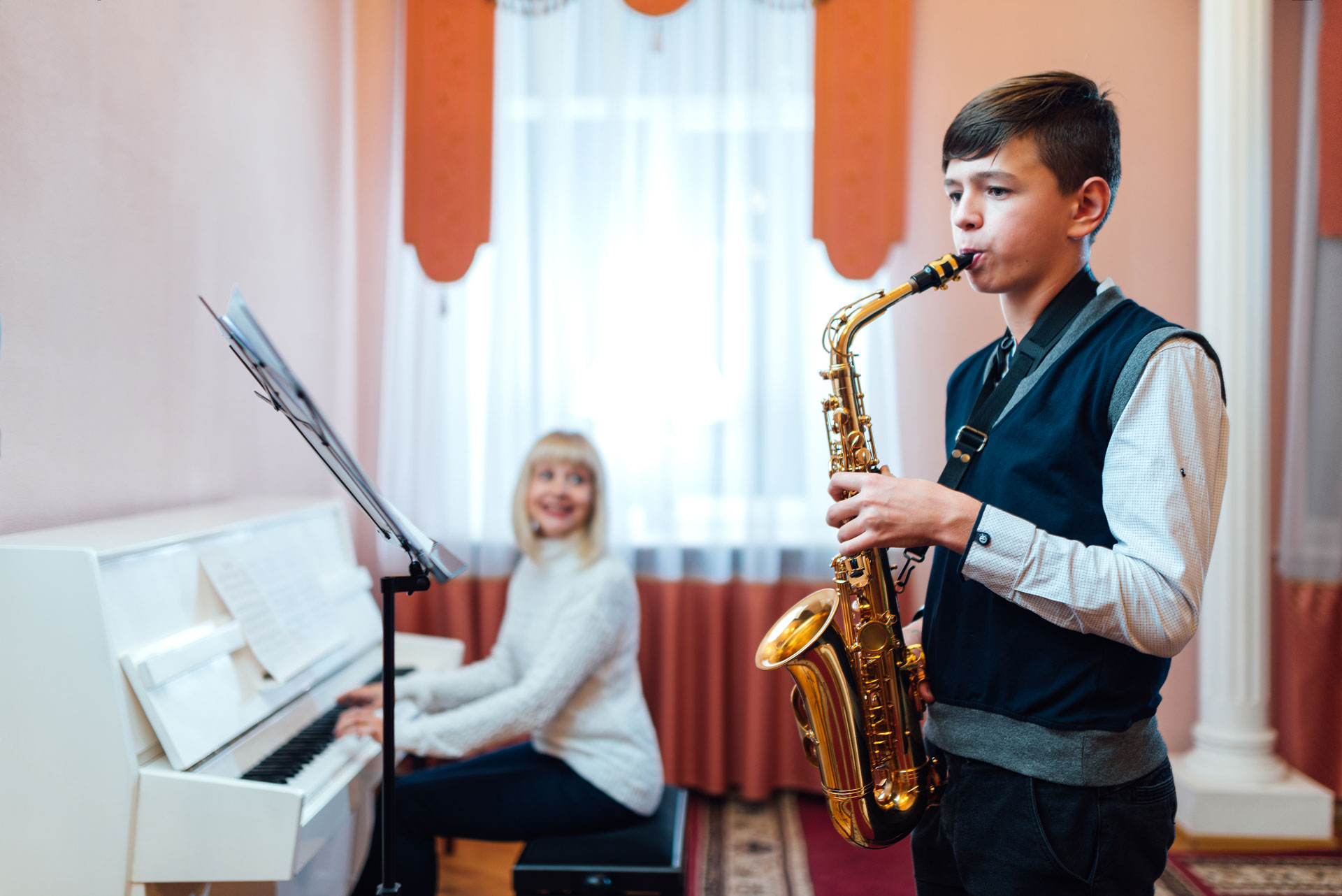 boy playing saxophone with female playing piano