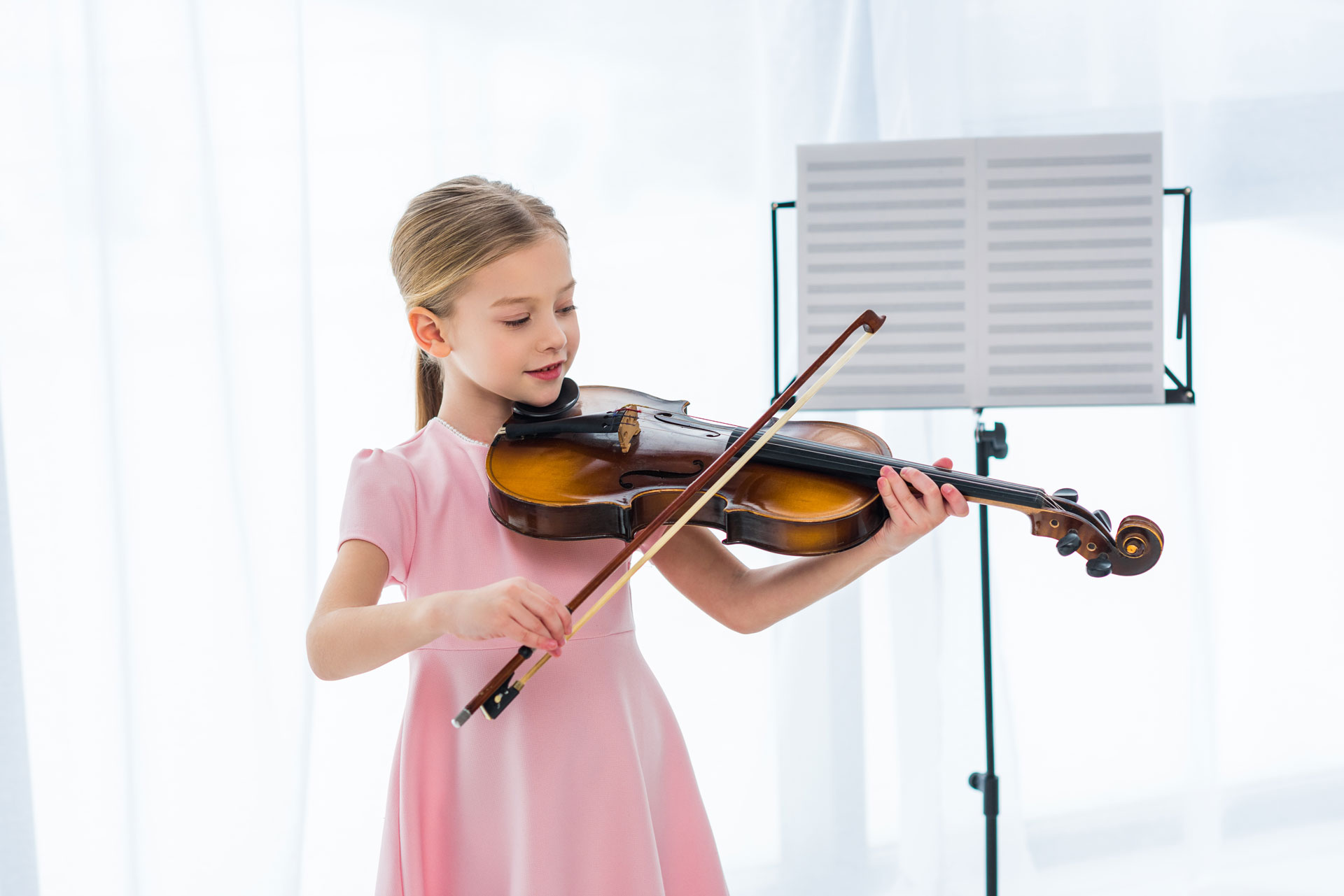 young girl in pink dress learning to play the violin