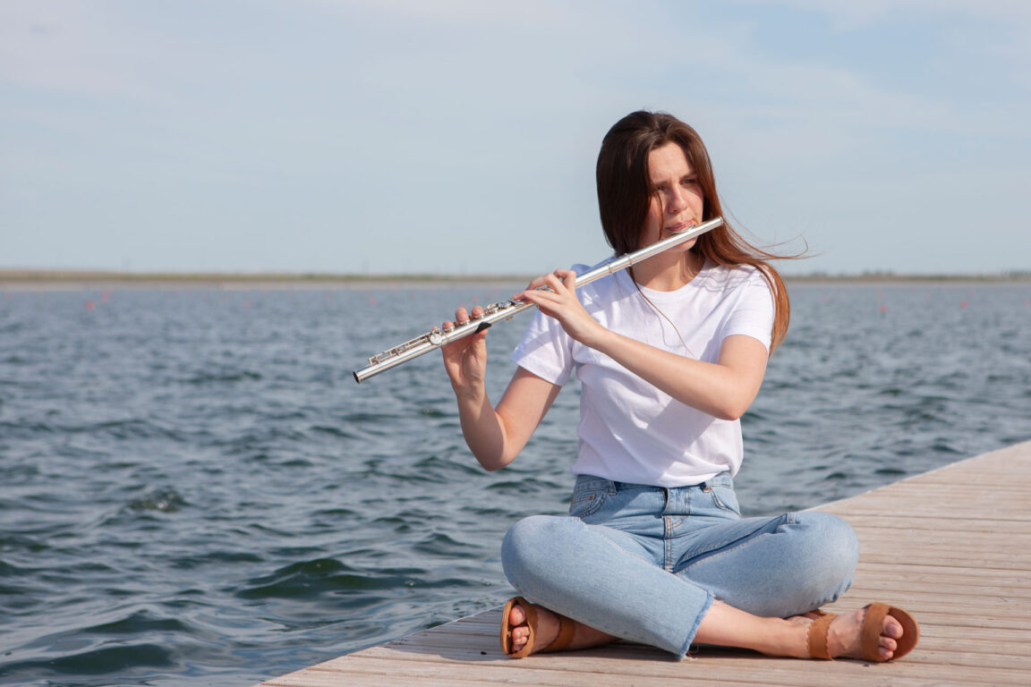 girl playing flute on a dock