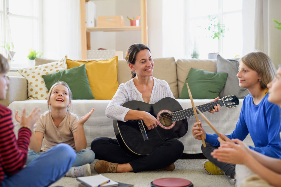 female teacher teaching music to group of children