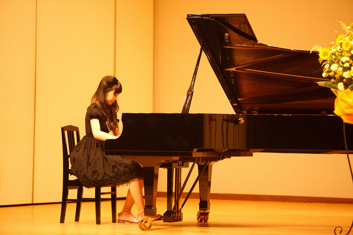 young girl playing piano at concert hall