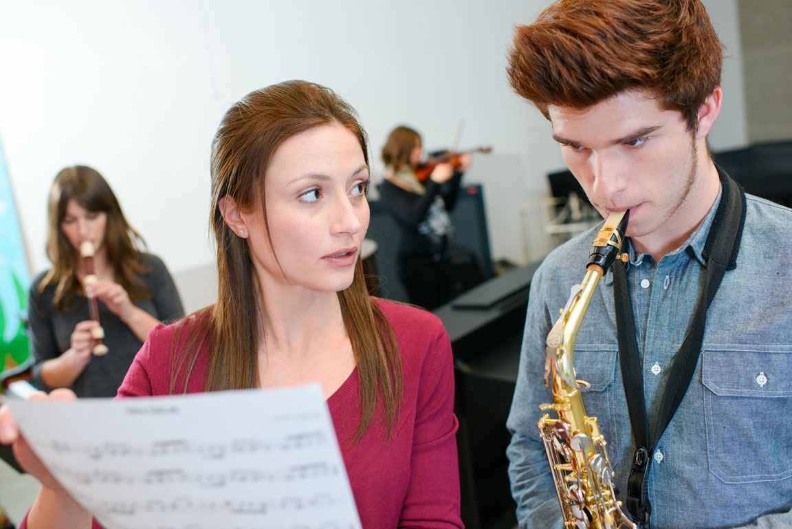music teacher working with saxophone student